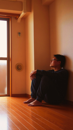 Persona sentada sola en un espacio tranquilo, con el pensamiento perdido en la nada, reflejando una calma exterior y un deseo de amar, pero no sabe a quién.